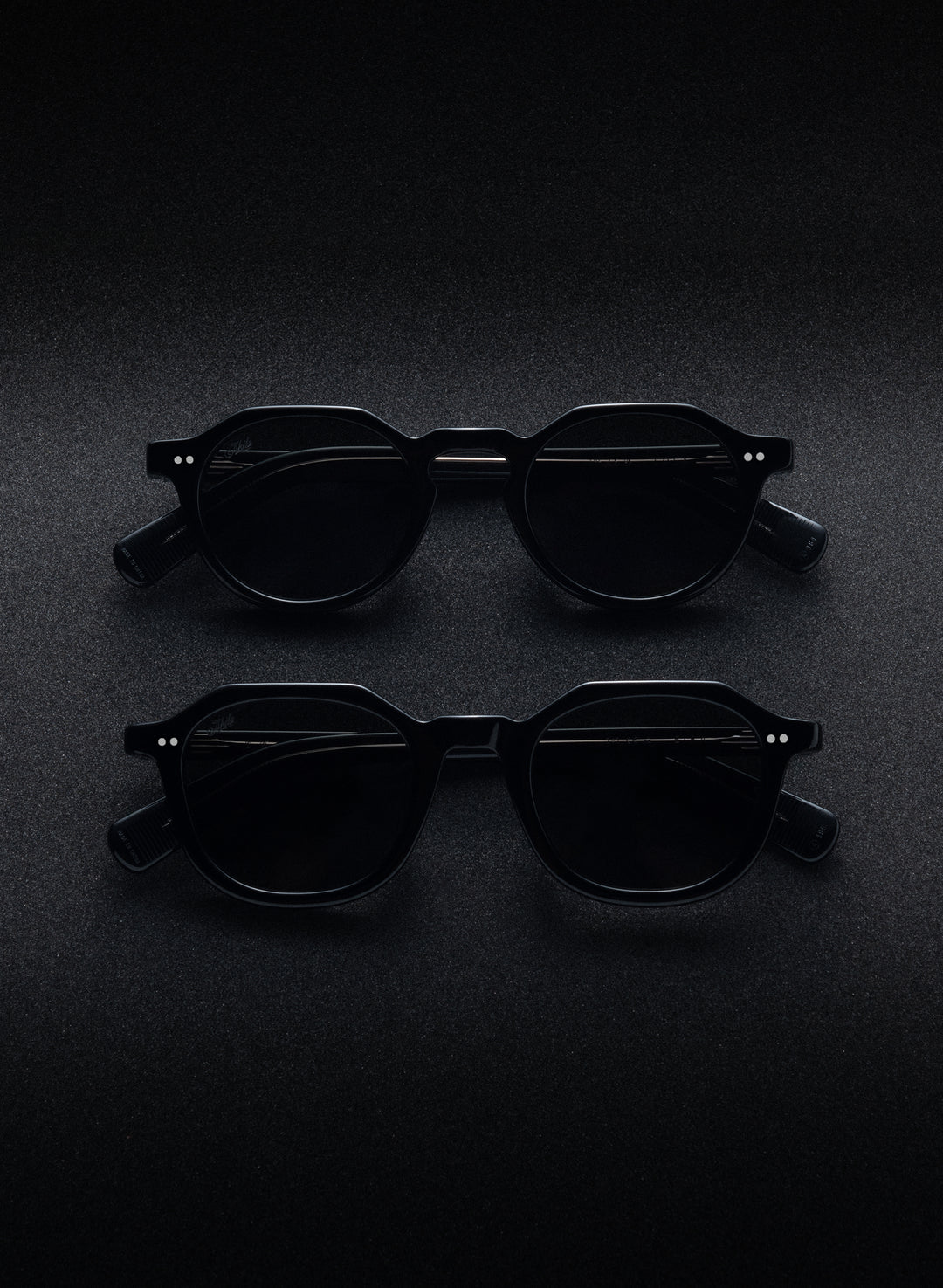 AKILA sunglasses photographed on a dark textured surface